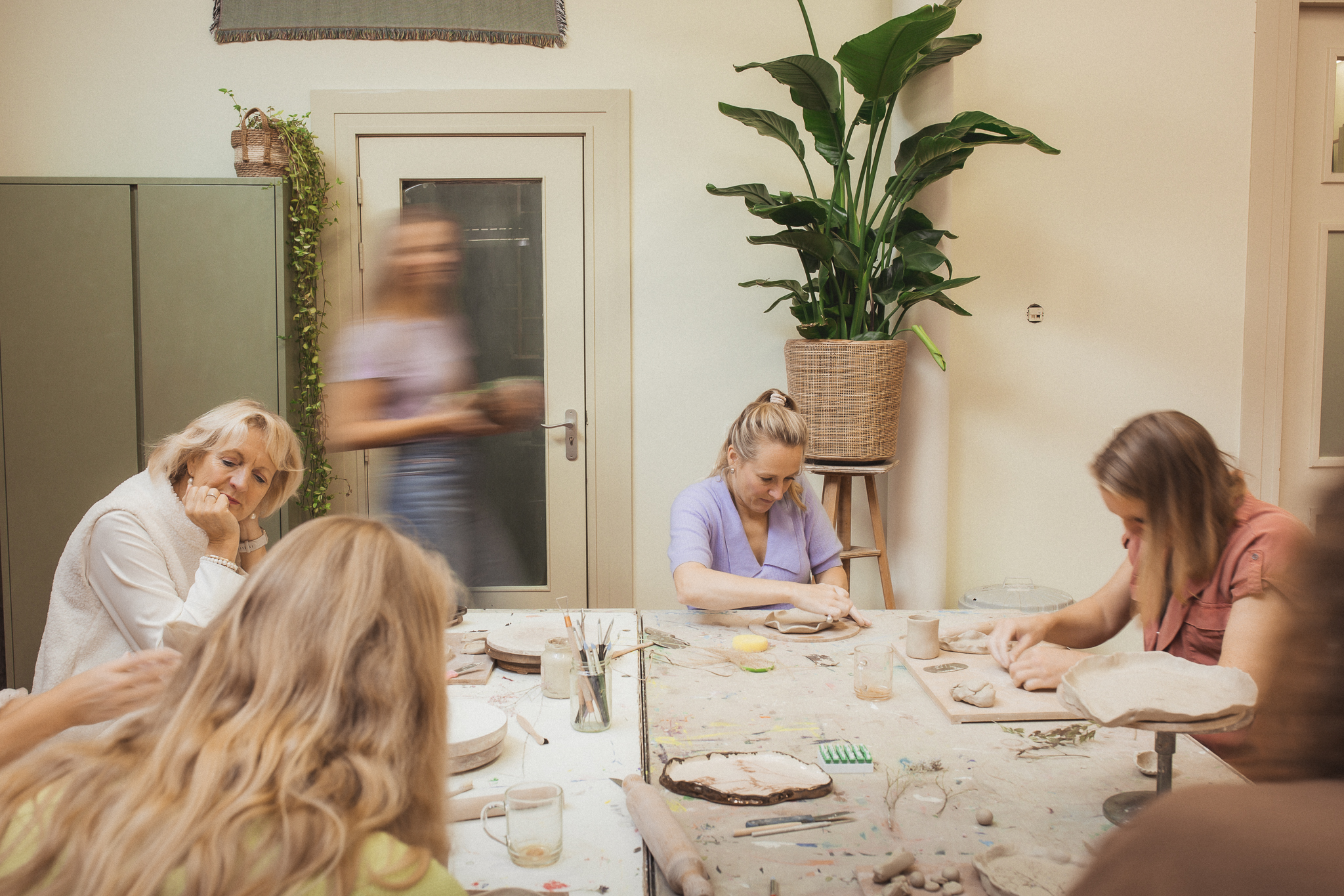 Keramist loopt rond tijdens kleiworkshop met instructies