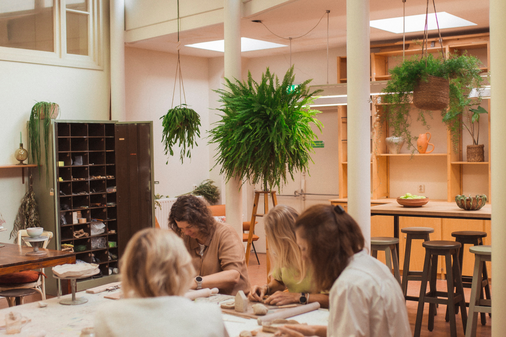 Lichte keramiekstudio met veel ruimte en plannen met cursisten aan het creëren